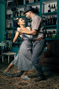 Two lovers dancing tango style in a vintage coffee room.