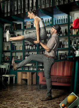 Couple dancing and jumping in a vintage coffee room.