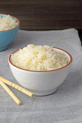 A bowl of cooked white rice on a linen towel with copy space for your text