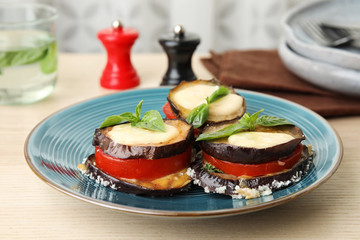 Baked eggplant with tomatoes, cheese and basil on table