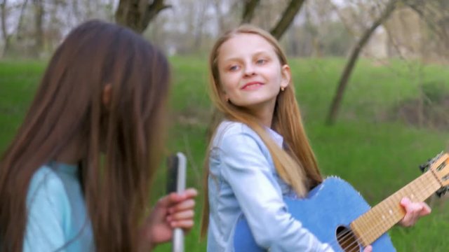 young children girlfriends amuse sing songs and dancing together playing guitar. have fun in nature