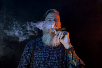 Portrait eines attraktiven Geschäftsmannes mit einer Zigarre und einem Glas Whiskey vor dunklem...
