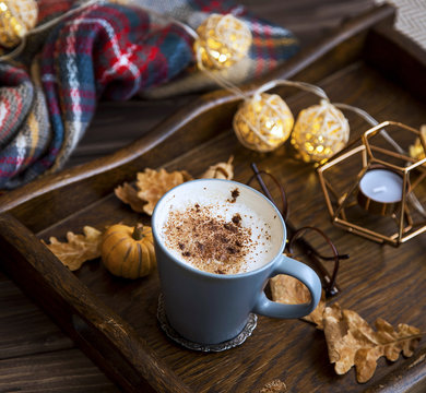 Cup of coffee or hot chocolate in a wooden tray, autumn cosy scarf and decorations