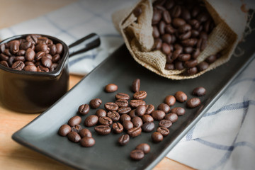 Coffee beans in the sackcloth on black plate