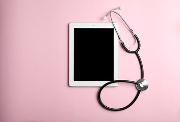 Stethoscope and tablet with space for text on color background, top view. Medical device