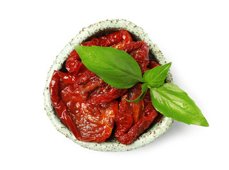 Bowl with sun dried tomatoes and green leaves on white background, top view