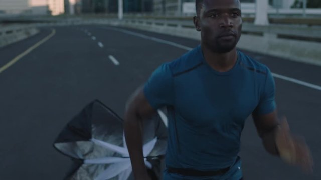close up african american athlete man using running parachute exercising resistance training muscular black male runner endurance jogging in urban city background