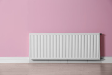 Modern radiator on color wall indoors. Central heating system