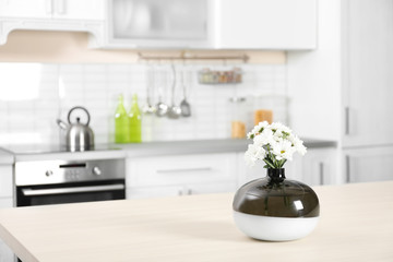Fototapeta na wymiar Vase with beautiful flowers on table in kitchen interior. Space for text