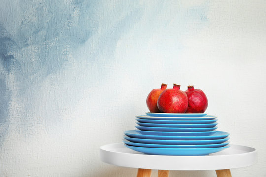 Stack of plates with pomegranates on table against light background, space for text. Interior element
