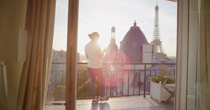 happy woman using smartphone texting on balcony in paris france enjoying view of eiffel tower sharing vacation experience browsing social media beautiful sunset