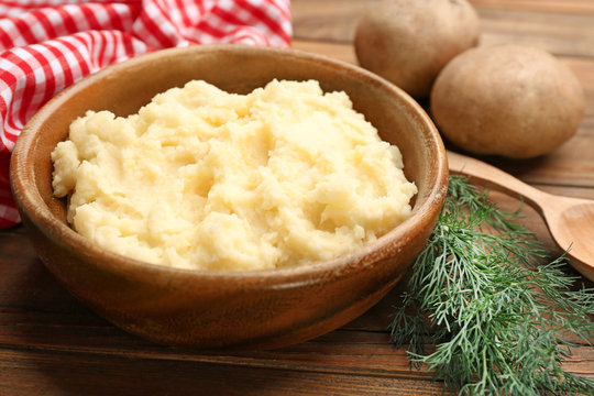 Bowl with tasty mashed potatoes on wooden table