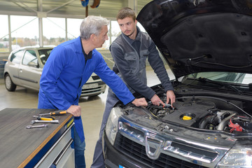 student mechanic learning from teacher in automotive vocational school