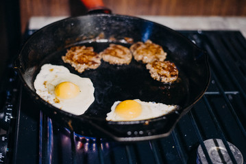 Sausage and eggs being cooked in cast iron skillet on a gas stove. Stove from RV. Full time RV lifestyle