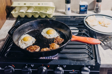 Sausage and eggs being cooked in cast iron skillet on a gas stove. Stove from RV. Full time RV lifestyle
