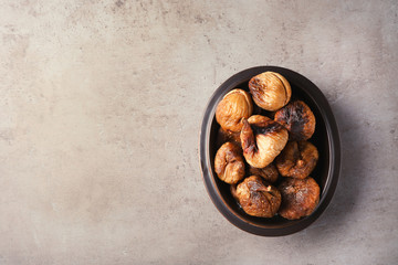 Bowl with dried figs on grey background, top view. Space for text