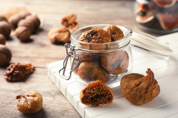 Jar with delicious dried figs on wooden board. Organic snack