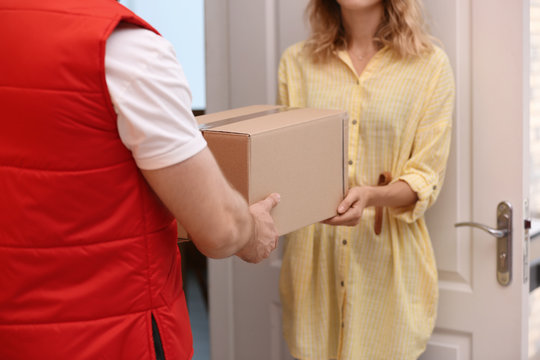 Woman receiving parcel from deliveryman indoors, closeup. Space for text