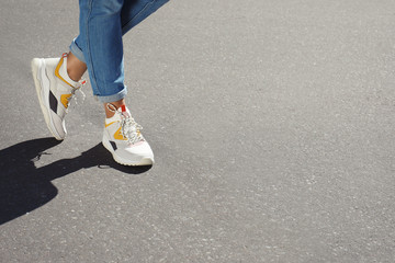 Fototapeta na wymiar Woman in stylish sneakers walking outdoors, focus on legs. Space for design