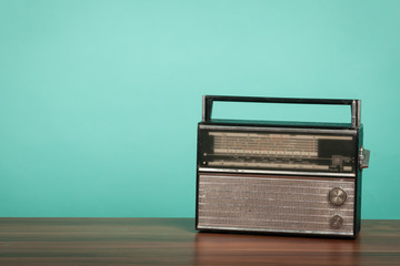 Old radio on table in front of green background. Vintage style photo