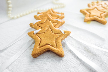 Decorative golden stars handmade from dough on a white fabric surface. Limited depth of field.