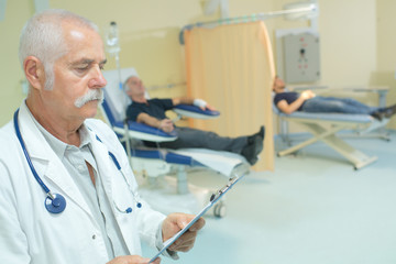 Doctor in ward holding clipboard