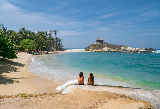 Back view of young couple sitting by the sea in Colombia, Tayrona