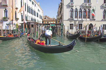 Fototapeta na wymiar Venetian gondolier in the gondola is transported tourists through canal waters of Venice Italy