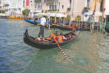 Fototapeta na wymiar Venetian gondolier in the gondola is transported tourists through canal waters of Venice Italy
