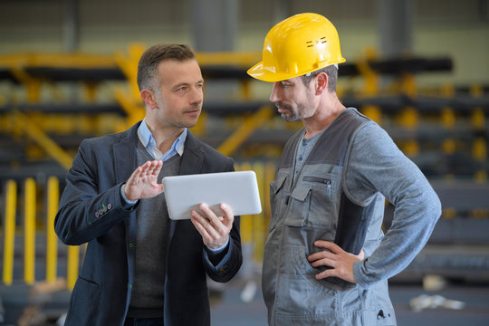 Men in industrial building looking at tablet