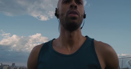young man runner stretching preparing for running workout performing warm up exercise in urban city enjoying healthy fitness lifestyle at sunset listening to music