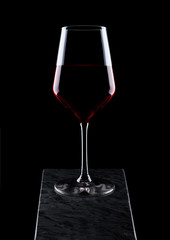 Elegant glass of red wine on wooden board on black background.