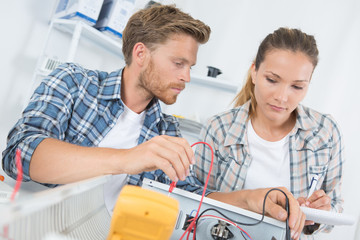 Two technicians testing appliance with multimeter