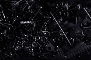 Abstract of Used Metallic knot screw nuts and nail bolts on dark background