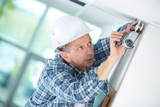 senior male technician installing camera on wall
