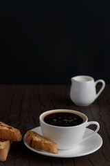 coffee and biscotti on a wooden table, dark background