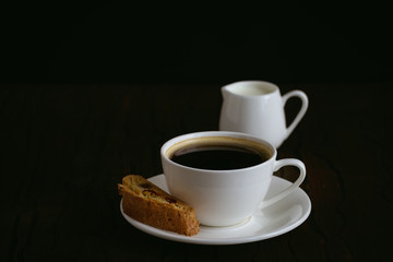 coffee and biscotti on a wooden table, dark background
