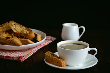 coffee and biscotti on a wooden table, dark background