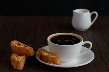 coffee and biscotti on a wooden table, dark background