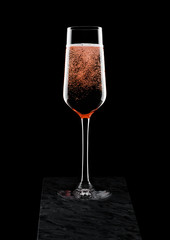 Elegant glass of pink rose champagne with bubbles on blavk marble board on black background.