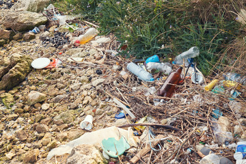 Spilled garbage on the beach of the big city. Empty used dirty plastic bottles. Dirty sea sandy shore the Black Sea. Environmental pollution. Ecological problem. Bokeh moving waves in the background