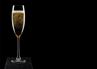 Elegant glass of yellow champagne with bubbles on blavk marble board on black background. Space for text