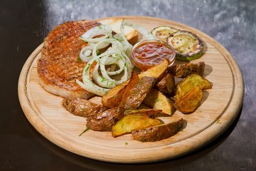 Grilled chicken meat with pickled onions and zucchini, french fries, served on wooden plate, beautiful food photo