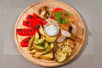 smoked sausages with grilled tomatoes, paprika, mushrooms, zucchini, fried potatoes, dill, white sour sauce, tasty flatlay food photo