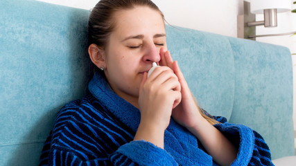 Closeup portrait of young woman feeling unwell using nasal spray