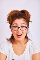 Obraz premium A girl in glasses smiles and looks with surprised eyes