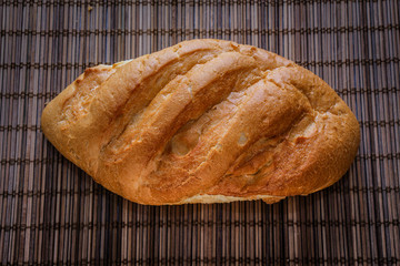 bread on the table just from the stove. freshly baked loaf of bread on a straw mat.