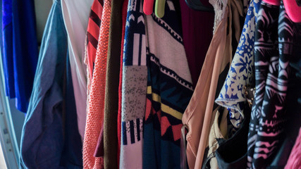 many colorful clothes hanging on pink hangers with different colors and patterns close up photo