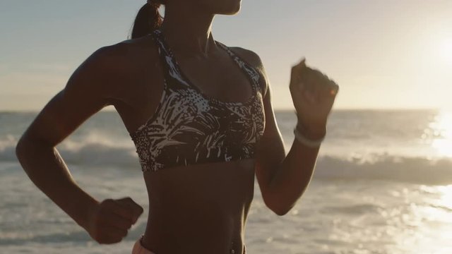 strong young african american woman running intense fitness workout challenge training active fitness lifestyle on beautiful seaside beach at sunrise slow motion