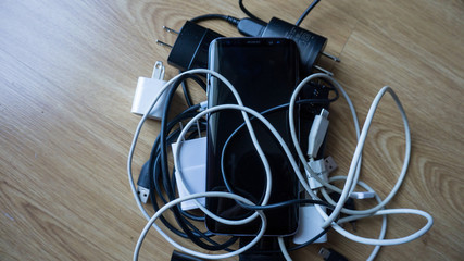Smartphone tangled in differnt electronics cables chargers usb 7 black and white wires. With copy...
